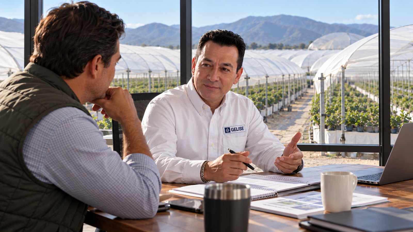 GELISE durante una conversación de gestión empresarial con un productor de berries, con macrotúneles de arándanos al fondo.
